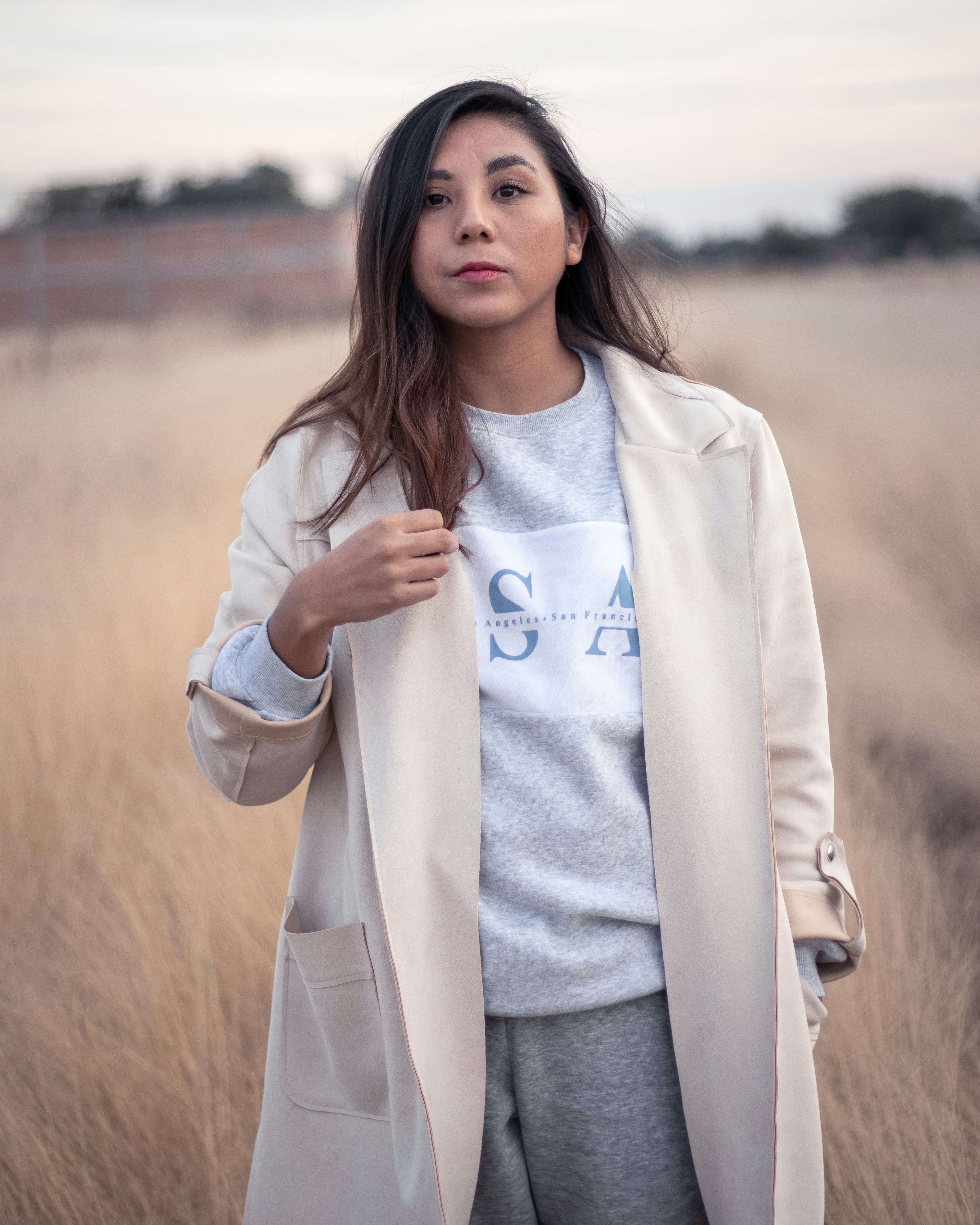 woman in white coat standing on field during daytime